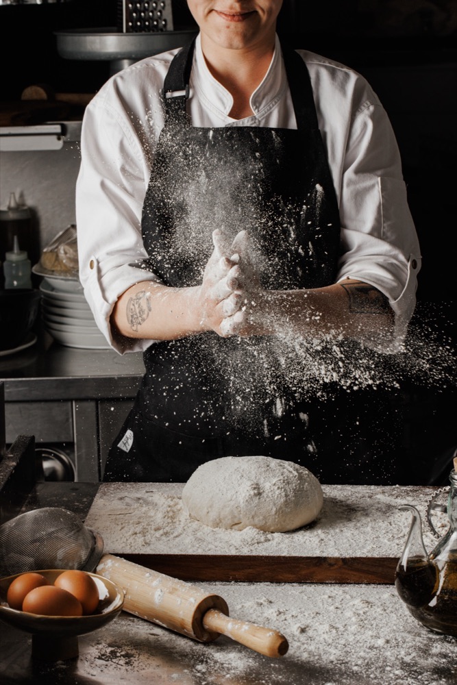 Chef shaping dough in a cloud of flour